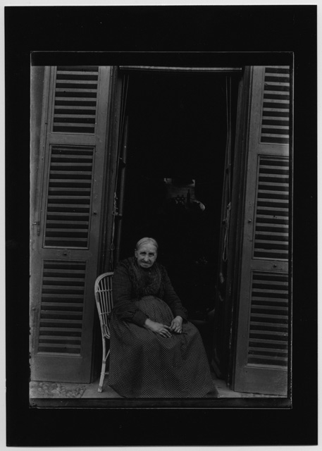 Ritratto di donna anziana seduta sull'uscio di casa