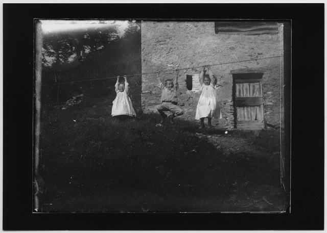 Ritratto di tre bambini che giocano appesi a una corda