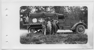 Tre soldati americani in posa davanti a un mezzo cingolato