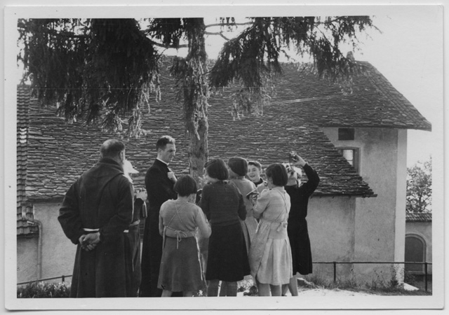 Gruppo di ragazzi in visita al Convento di Bigorio con un prete e un frate