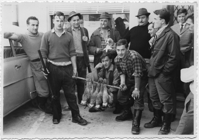 Gruppo di cacciatori in posa con quattro lepri