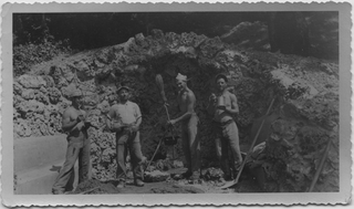 Gruppo di operai in posa davanti ad una grotta in costruzione