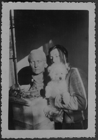 Mario Bernasconi con il cane vicino a una sua scultura