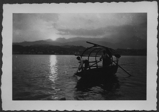Pescatori raccolgono le reti al tramonto sul lago di Lugano