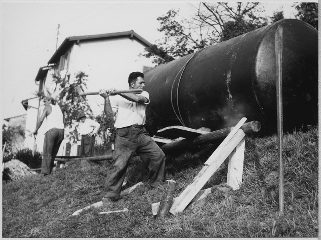 Uomini al lavoro durante la posa di una cisterna a Roveredo