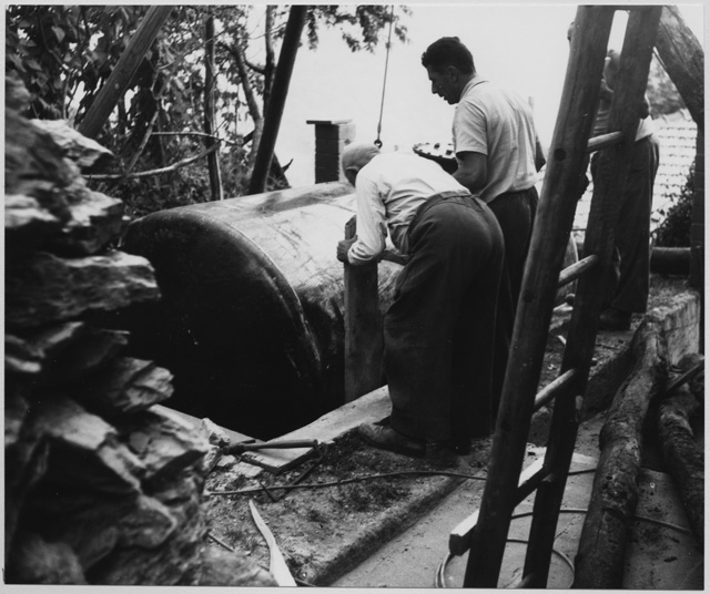 Uomini al lavoro per la posa di una cisterna a Roveredo