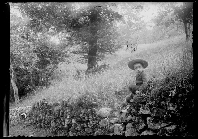 Bambino in posa sopra a un muretto