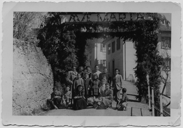 Ragazzi in posa sotto una porta trionfale a Bidogno