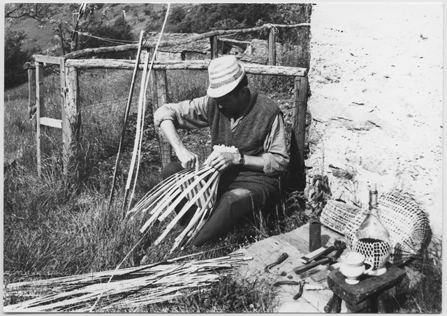 Cestaio mentre intreccia una gerla ai monti di Brena