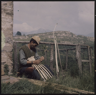 Cestaio mentre intreccia una gerla ai monti di Brena