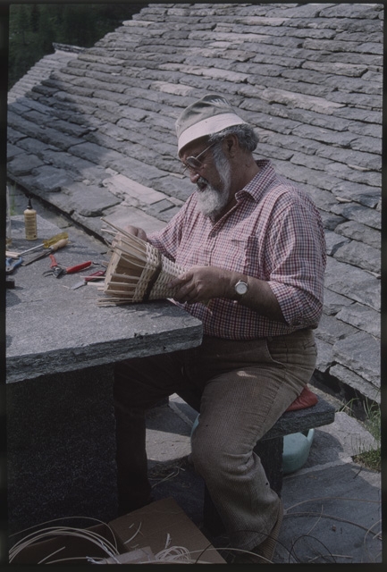 Uomo mentre intreccia un cestino di vimini