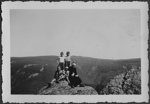 Gruppo Scout in posa sopra a una roccia con Don Ugo Campana