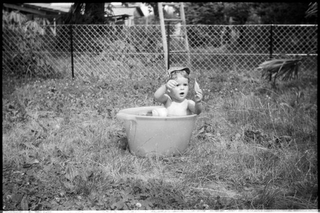 Ritratto di bambino che fa il bagno in un catino in giardino