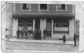 Cartolina con emigranti in posa davanti ad un negozio